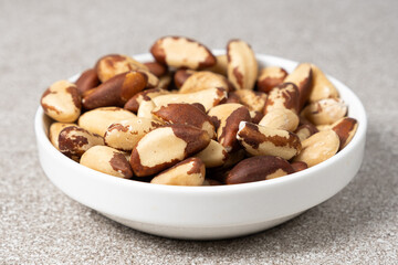 Brazil nuts in plate on grey background