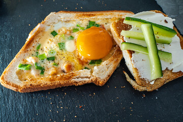 A delicious and healthy breakfast close-up. On a black mica board, toasted toast with egg, cheese...