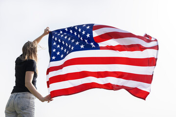 unrecognizable woman holds a large waving American flag in her hands. Celebrate Independence Day. National symbol of freedom of the States of America. Bright future. patriotic holiday