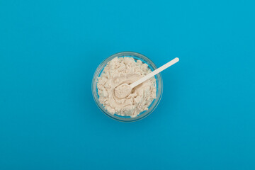 Guar gum powder or guaran in glass bowl with plastic measuring spoon top view. Food additive E412. Thickening agent. Guar Gum widely used in dairy products. Texture improver and improves creaminess