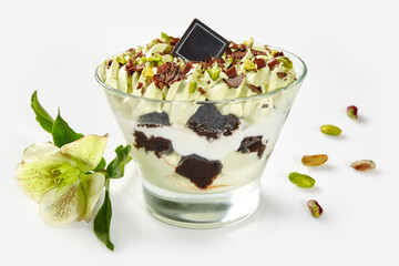 Glass of pistachio and chocolate layered dessert with floral accent