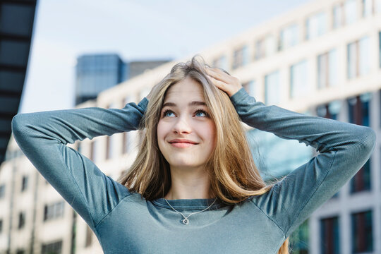 Smiling blond teenage girl with hands in hair
