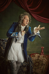Elderly man dressed historical baroque-style attire, looks as lord, singing to megaphone against...
