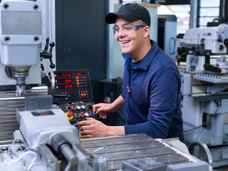 Happy apprentice operating CNC machine at factory