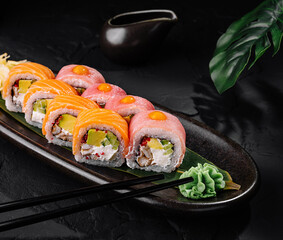 Gourmet sushi roll platter on black stone background