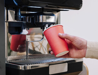 Hand filling red cup at coffee machine