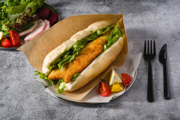 Fried fish sandwich with greens on the stone table. Turkish name Balik Ekmek