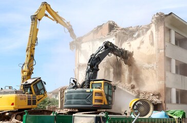 Two heavy excavators demolishing an old building for an urban redevelopment.