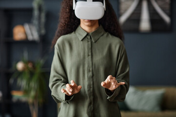 Selective focus shot of unrecognizable young woman wearing VR headset typing on virtual computer...