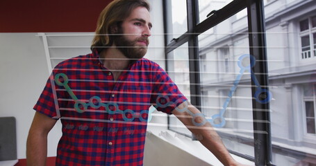 A young Caucasian professional wearing red plaid shirt, gazing out a window