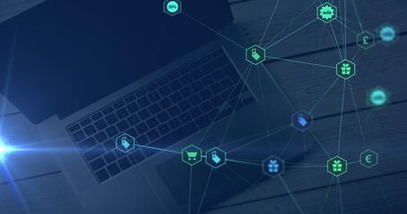 Naklejka premium Blue light trail and network of digital icons against laptop on wooden table