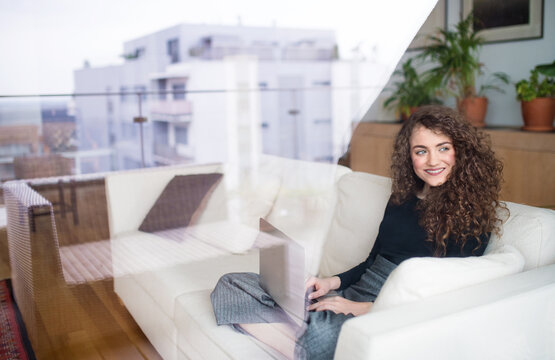 Beautiful woman working on laptop at home, homeoffice for young worker. Student studying at home, preparing for final exam.