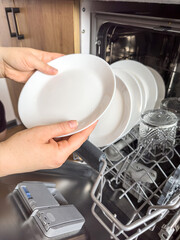 close up woman taking out clean dishes from dishwasher machine. Housewife does   housework