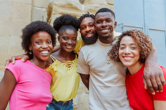 Happy multi ethnic young group of people looking at camera together outdoors - Lifestyle concept with guys and girls having fun hanging out on city street - Cheerful students portrait outside school