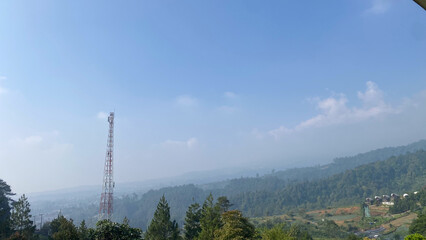 Obraz premium a red and white radio tower stands in the distance with forest and mountain in the background