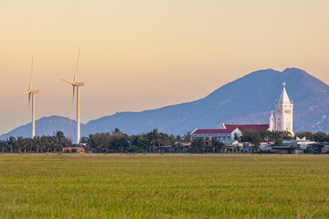 Landscape with rice fields and wind turbines and a Catholic church at Phan Rang, Ninh Thuan...