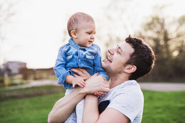 Father holding little toddler boy playing, having fun during warm spring day. Father's day concept.