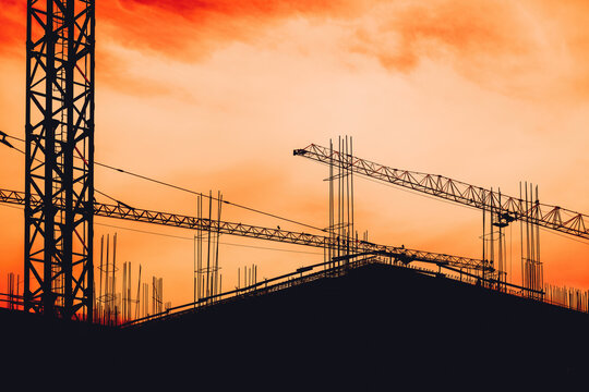 Construction site building scaffold and cranes in silhouette