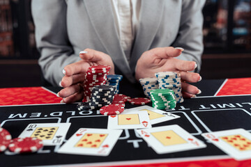 Gambler female hands going all-in, stack of colored poker chips at casino