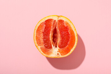 Half of a grapefruit on a pink background.