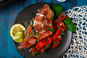 Baked redfish or perch with vegetables served on the plate on the blue table. Healthy fish dish. Top view