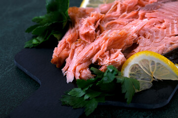 Hot smoked trout fillet served on the black board with lemon and parsley