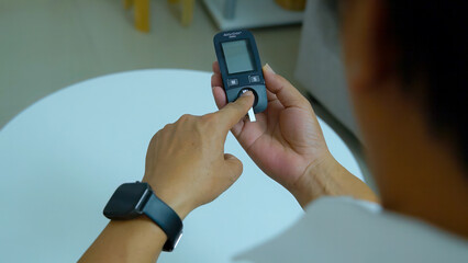 A Middle-aged Asian man measuring blood pressure at home health care concept.