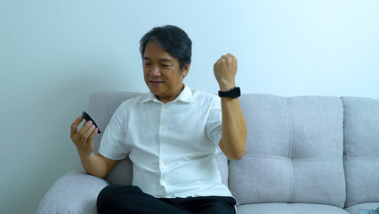 A Middle-aged Asian man happy measuring blood pressure at home health care concept.