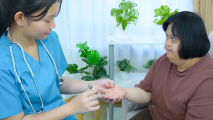 Asian female nurse uses a diabetes test device for a woman with Down syndrome at home.