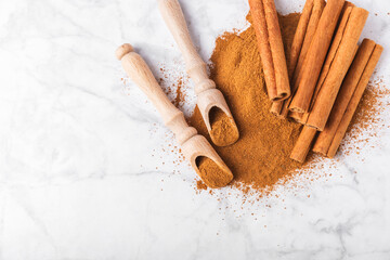 Cinnamon powder in a bowl on a textured wooden background. Spicy spice for baking, desserts and drinks. Fragrant ground cinnamon. Cinnamon stick. Place for text. Copy space.
