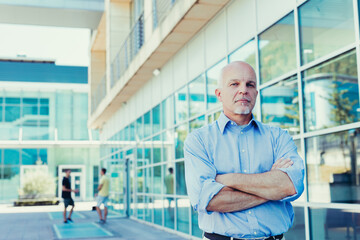 Mature businessman poses, authority by glass office