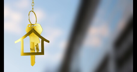Golden key shaped like house hanging against blue sky