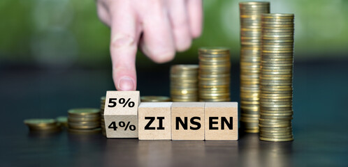 Hand turns wooden cube and changes the German expression '4 prozent Zinsen' (4 percent interest...