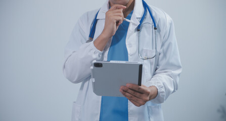 Mature male doctor with tablet pc is giving presentation. Blurred background indoors.