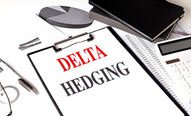 DELTA HEDGING text on clipboard on chart with notebook and calculator