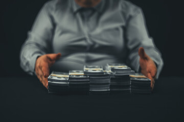Out of focus. A man adjusts stacks of dollar bills on a black background. A man in a white business shirt folds stacks of dollar bills on a black background. Even stacks of wads of money.