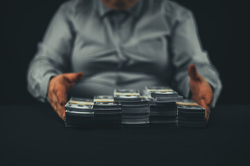 Out of focus. A man adjusts stacks of dollar bills on a black background. A man in a white business shirt folds stacks of dollar bills on a black background. Even stacks of wads of money. - Powered by Adobe