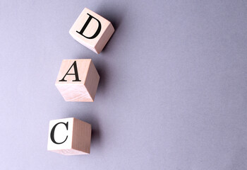 DAC word on wooden block on gray background