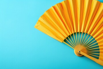 Close up of a yellow fan on a blue background. Great for summer themed designs