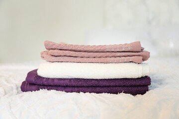 a stack of colorful cotton towels on the bed