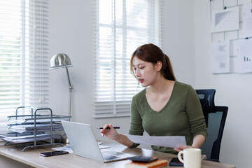 Young Asian business woman working on a laptop doing tax, accounting, statistics and analytical research concept.