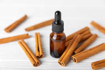 Cinnamon aromatic essential oil and cinnamon sticks on a wooden background. Aromatherapy. Organic cosmetic oil. Spa concept. Place for text. Copy space.