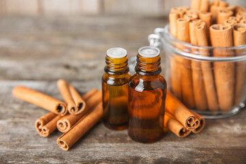 Cinnamon aromatic essential oil and cinnamon sticks on a wooden background. Aromatherapy. Organic cosmetic oil. Spa concept. Place for text. Copy space.