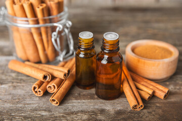 Cinnamon aromatic essential oil and cinnamon sticks on a wooden background. Aromatherapy. Organic...