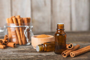 Cinnamon aromatic essential oil and cinnamon sticks on a wooden background. Aromatherapy. Organic cosmetic oil. Spa concept. Place for text. Copy space.
