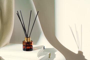 Liquid home perfume in glass diffuser with sticks on chair