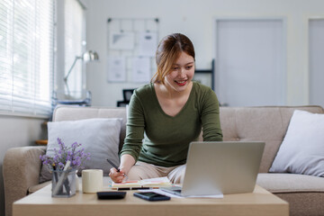 Asian business woman working on a laptop on couch, tax, accounting, statistics and analytical research concept.