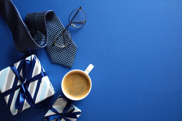 Fototapeta premium Stylish men’s gift set with coffee, glasses, and tie on blue background - perfect for Happy Fathers Day theme.