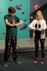 Obraz premium young girl at a climbing wall with a trainer doing a warm-up before rock climbing training