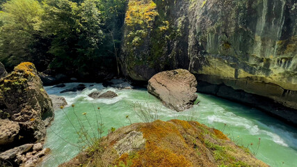 Turquoise river flowing through a rocky gorge surrounded by lush greenery, ideal for nature and...